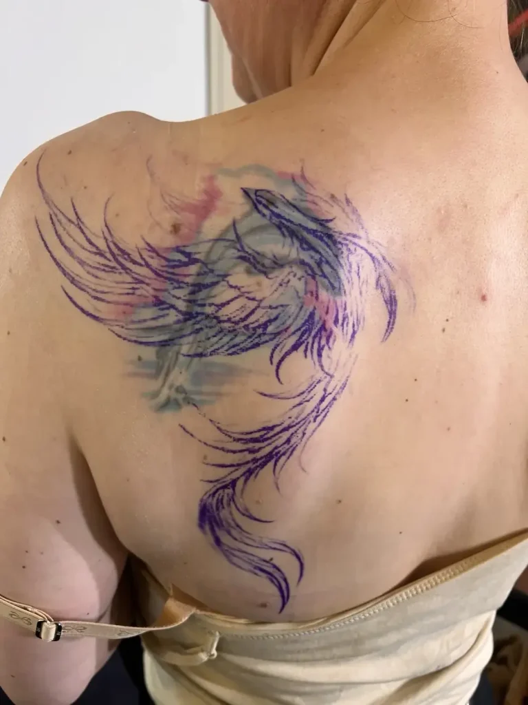 Tattoo vor dem Cover-Up: Phönix über altem Schriftzug